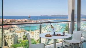 A balcony with a table, chairs, and a view of a marina and ocean. - Hotel Catalunya (Alghero)