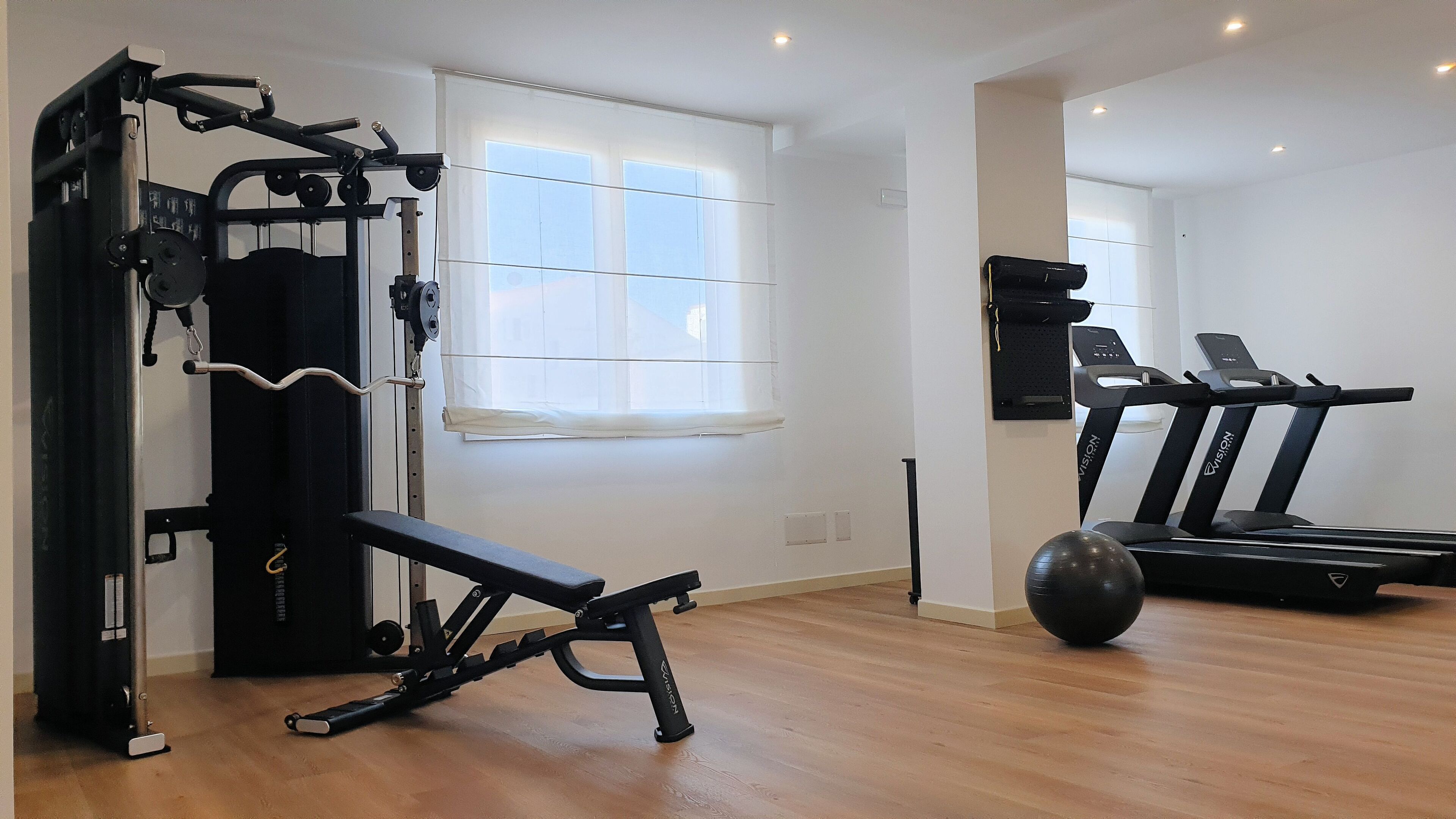 Een huisgym met een bankdrukapparaat, een loopband en een hometrainer.