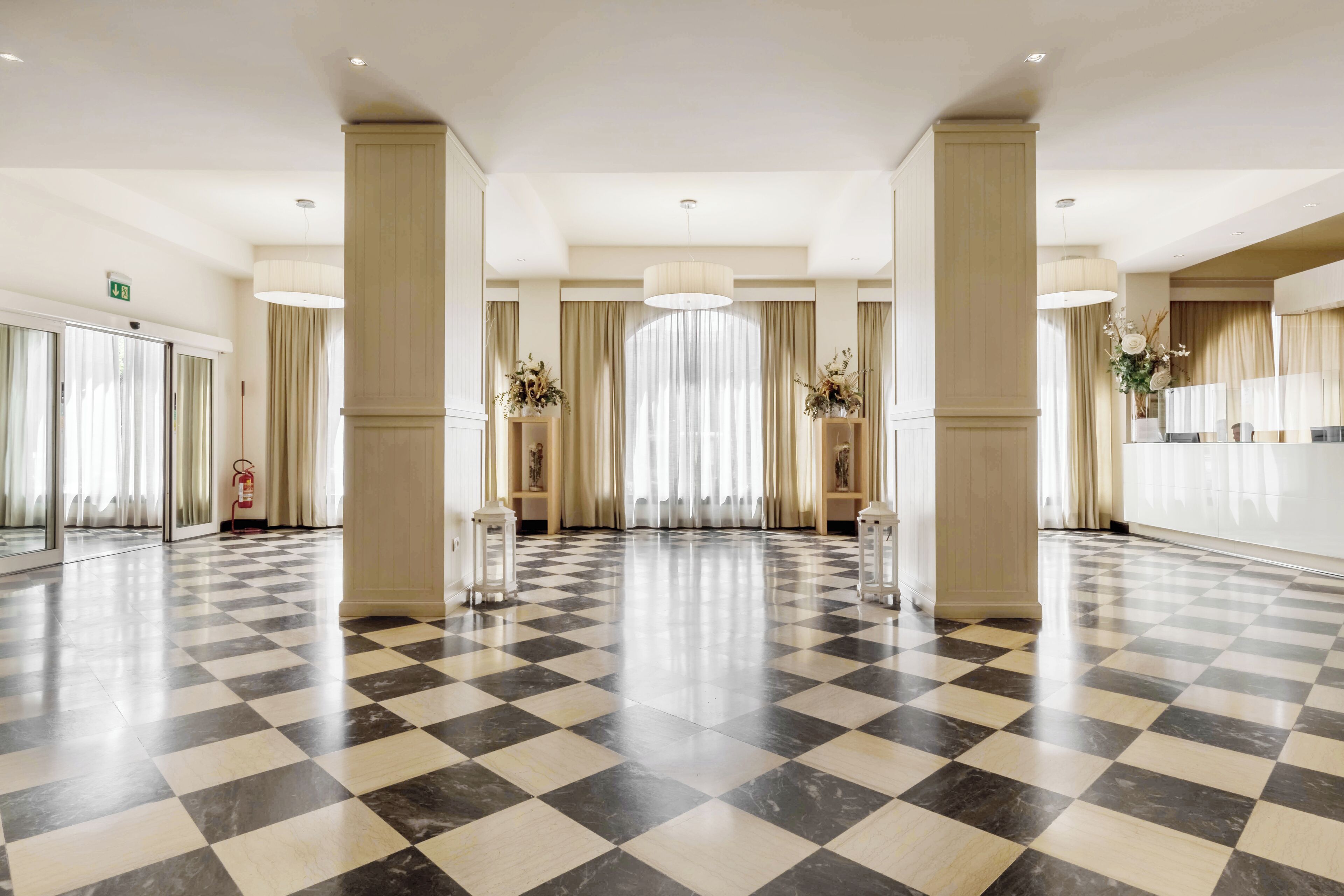 A spacious lobby with a checkered floor, large columns, and a reception desk.
