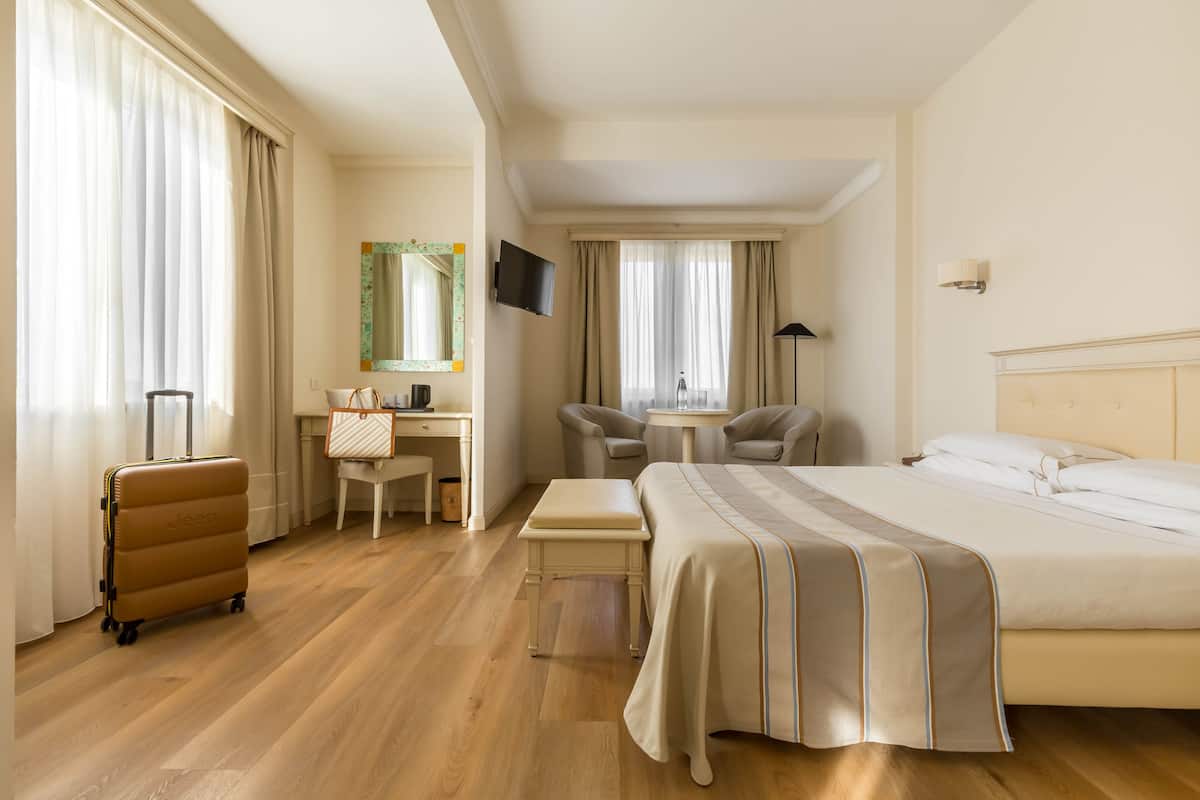 Una habitación de hotel con cama, escritorio, silla y maleta.
