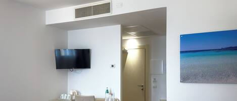 Una habitación de hotel con una cama, un escritorio, una silla, un televisor y una puerta que da a otra habitación.
