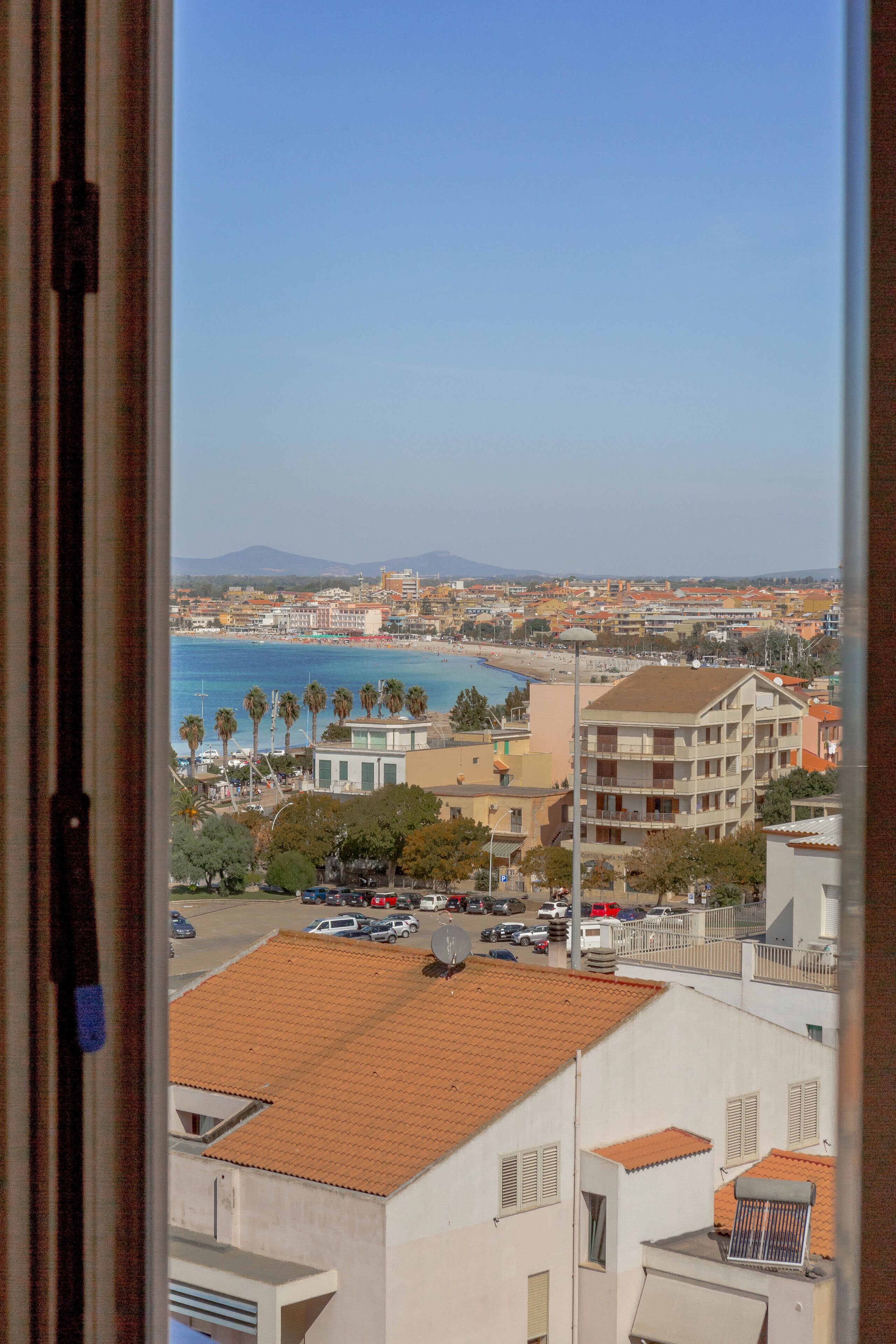 Un paysage urbain côtier avec des bâtiments, une plage et des palmiers.