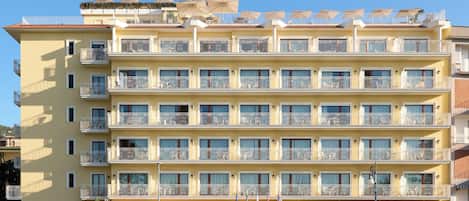 A multi-story hotel with balconies, a sign reading 'JelaVille,' and a clear blue sky.
