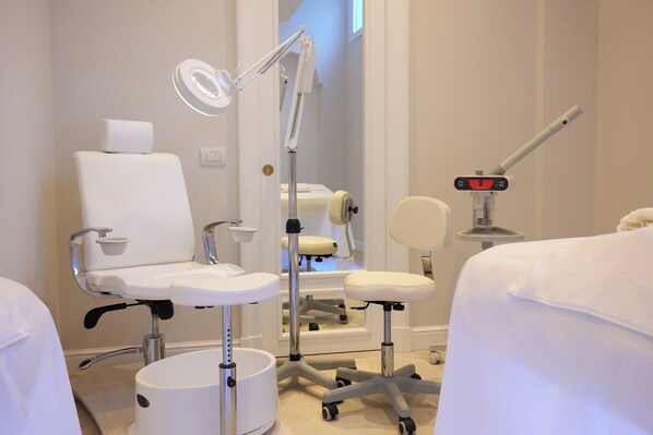 A clinical examination room with a white examination chair, a medical light, and a digital device on a stand. - Grand Hotel De La Ville (Sorrento)