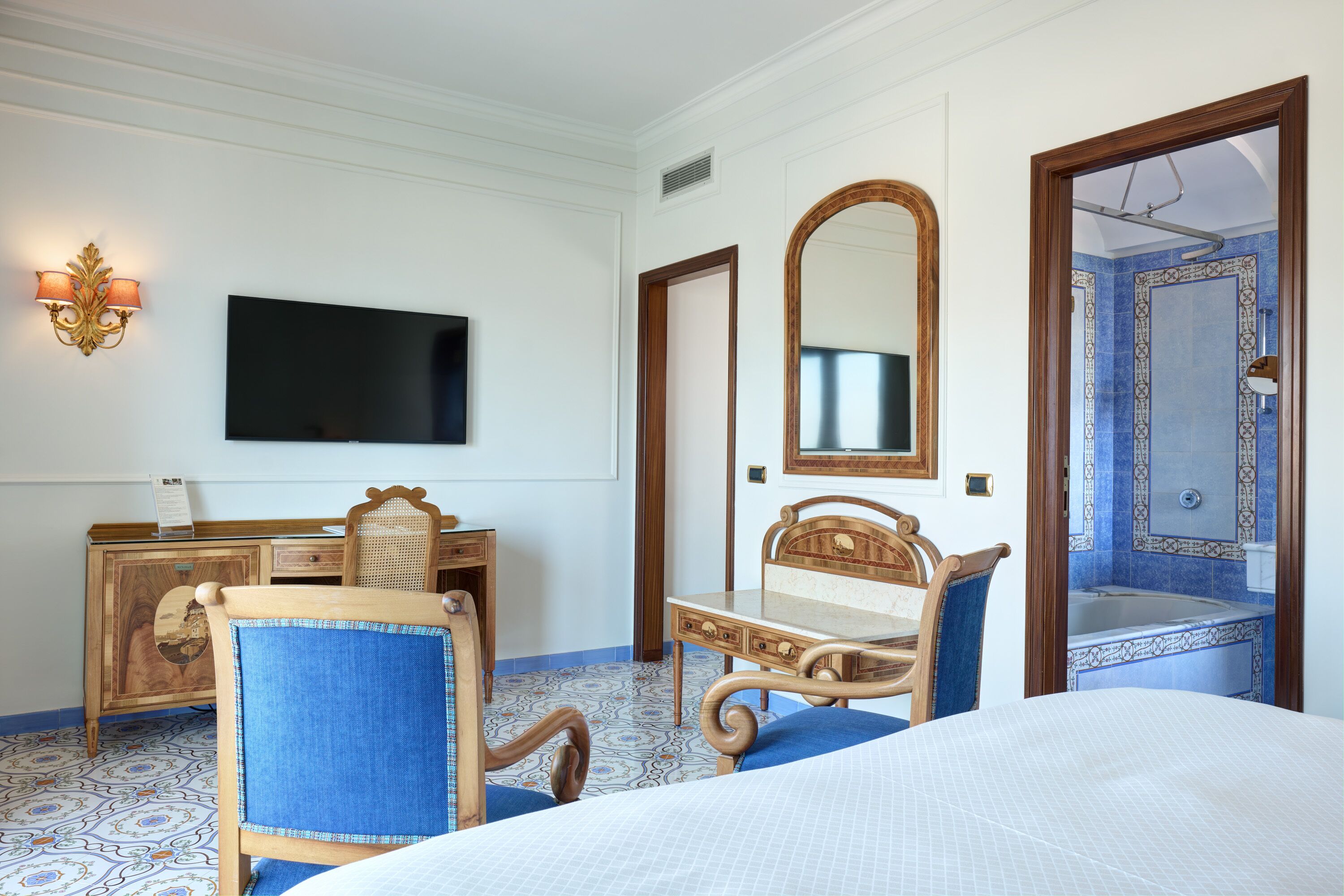 Ein Hotelzimmer mit Bett, Schreibtisch mit Stuhl, Fernseher, Spiegel und einem Badezimmer mit Badewanne.