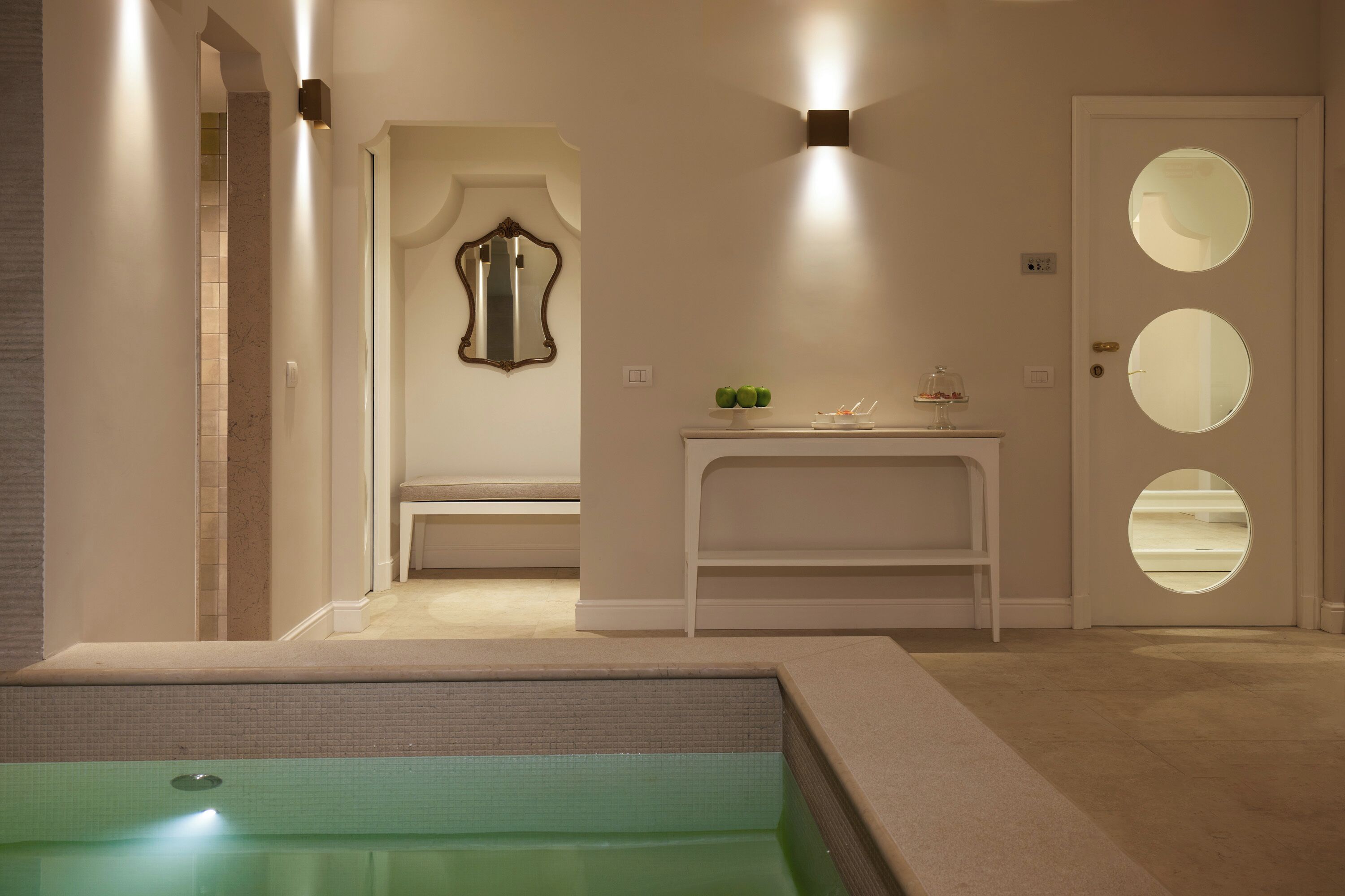 A modern bathroom with a bathtub, a vanity with a mirror, and a door with circular windows.