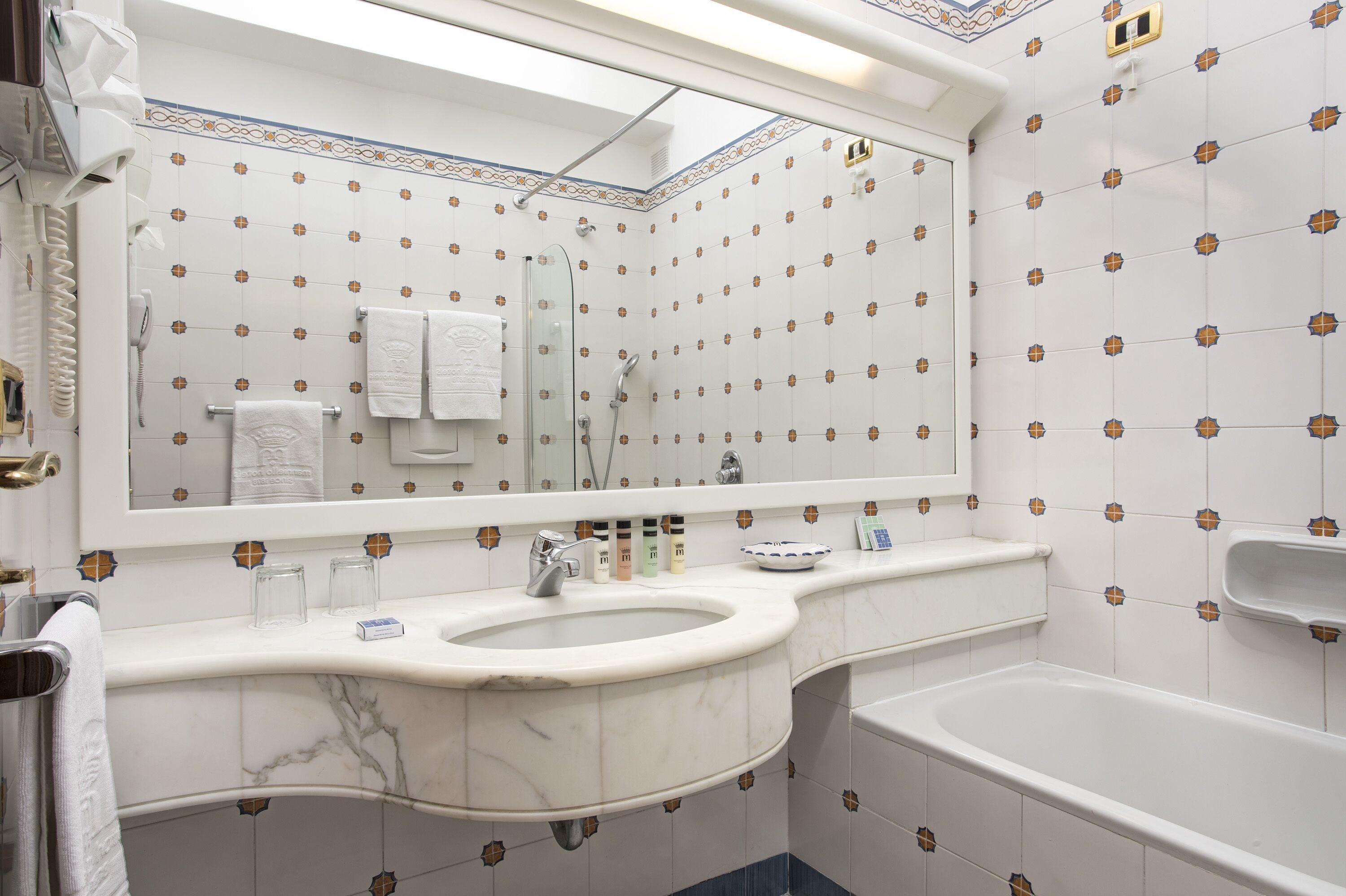 Un baño con un espejo grande, un lavamanos y una bañera.