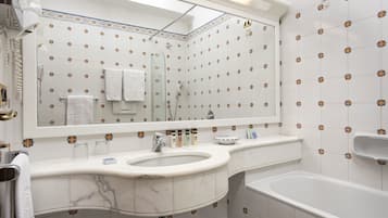 Un baño con un espejo grande, un lavamanos y una bañera.