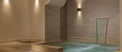 Zona de spa con jacuzzi, escalones que bajan al agua e iluminación empotrada.
