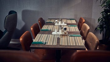 Une salle de conférence avec une longue table, des fauteuils en cuir marron et un chemin de table à rayures.
