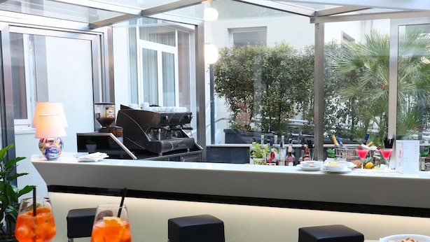 A restaurant with a modern interior, featuring a glass ceiling, a coffee machine, and a variety of dishes and drinks on the tables. - Grande Albergo Maugeri (Acireale)