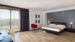 A hotel room with a bed, a desk, a chair, and a view of the city. - Grand Hotel Tiziano e dei Congressi (Lecce)