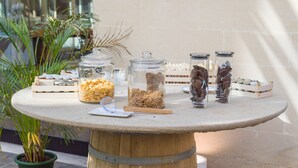 A round table with glass jars containing various items, a wooden barrel, and a potted plant. - Grand Hotel Tiziano e dei Congressi (Lecce)