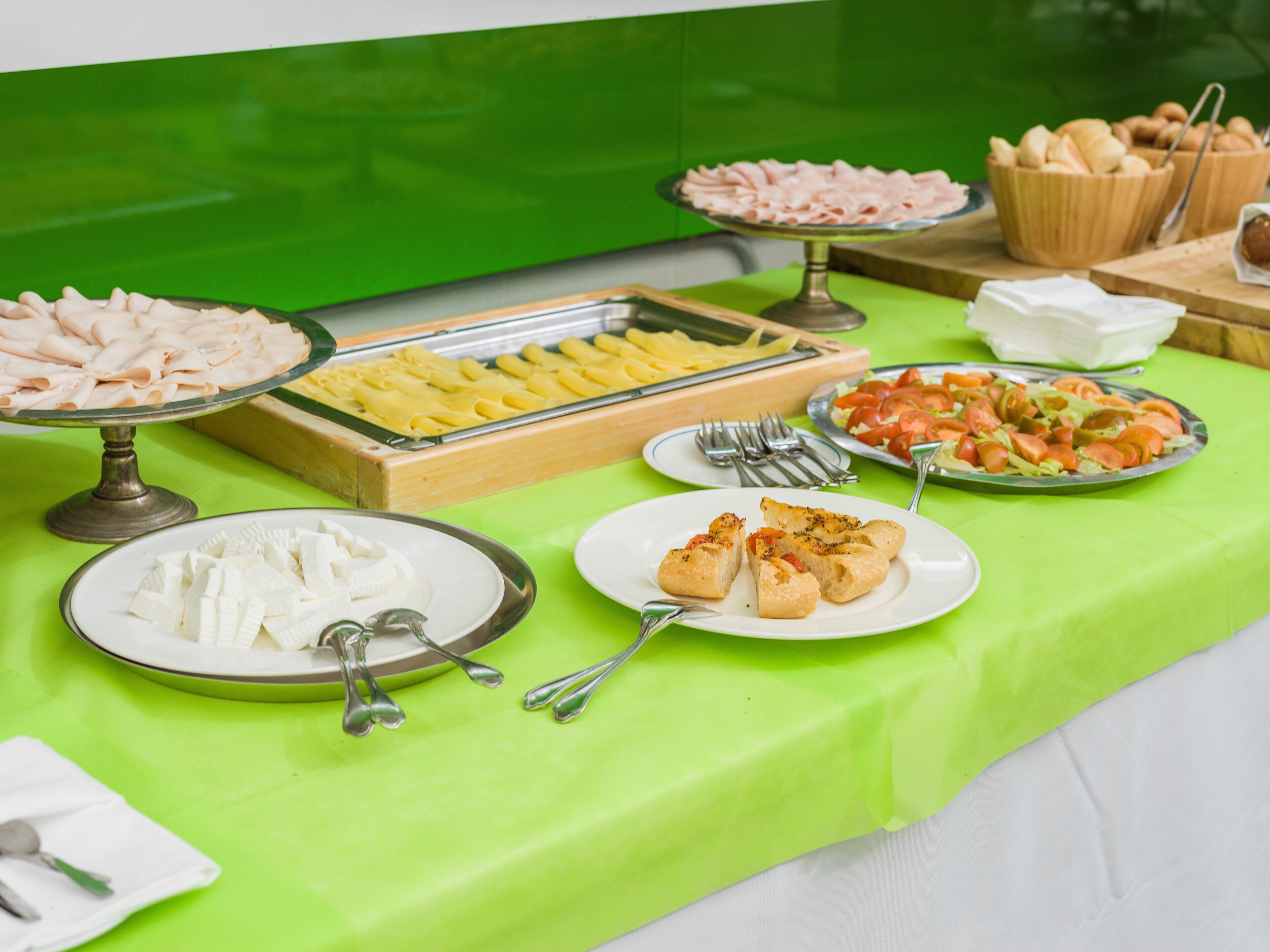 A buffet table with various food items including sliced meats, pasta, and vegetables.