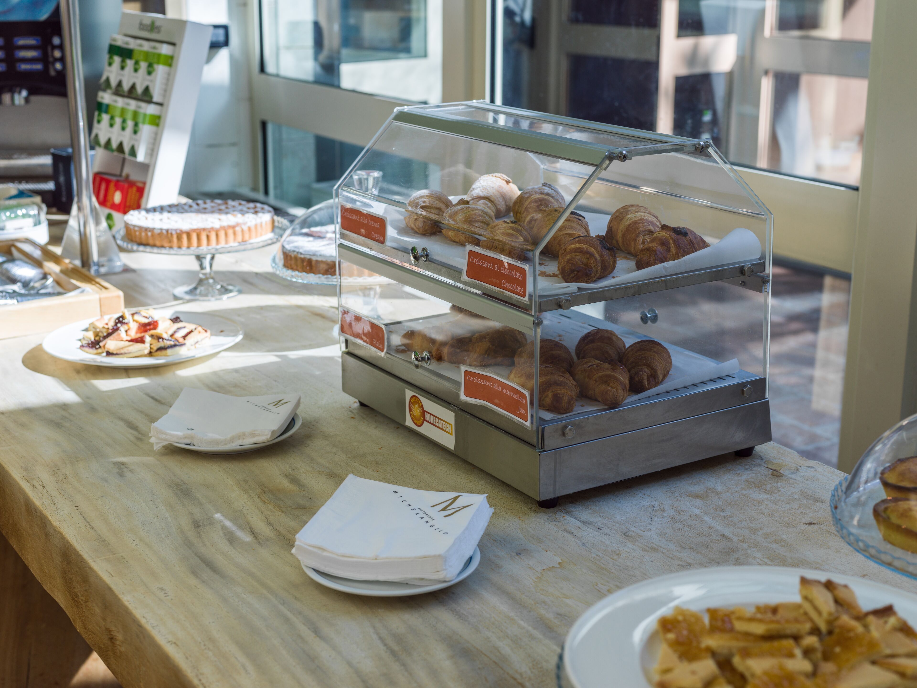 Una vetrina di pasticceria con croissant e altri dolci.