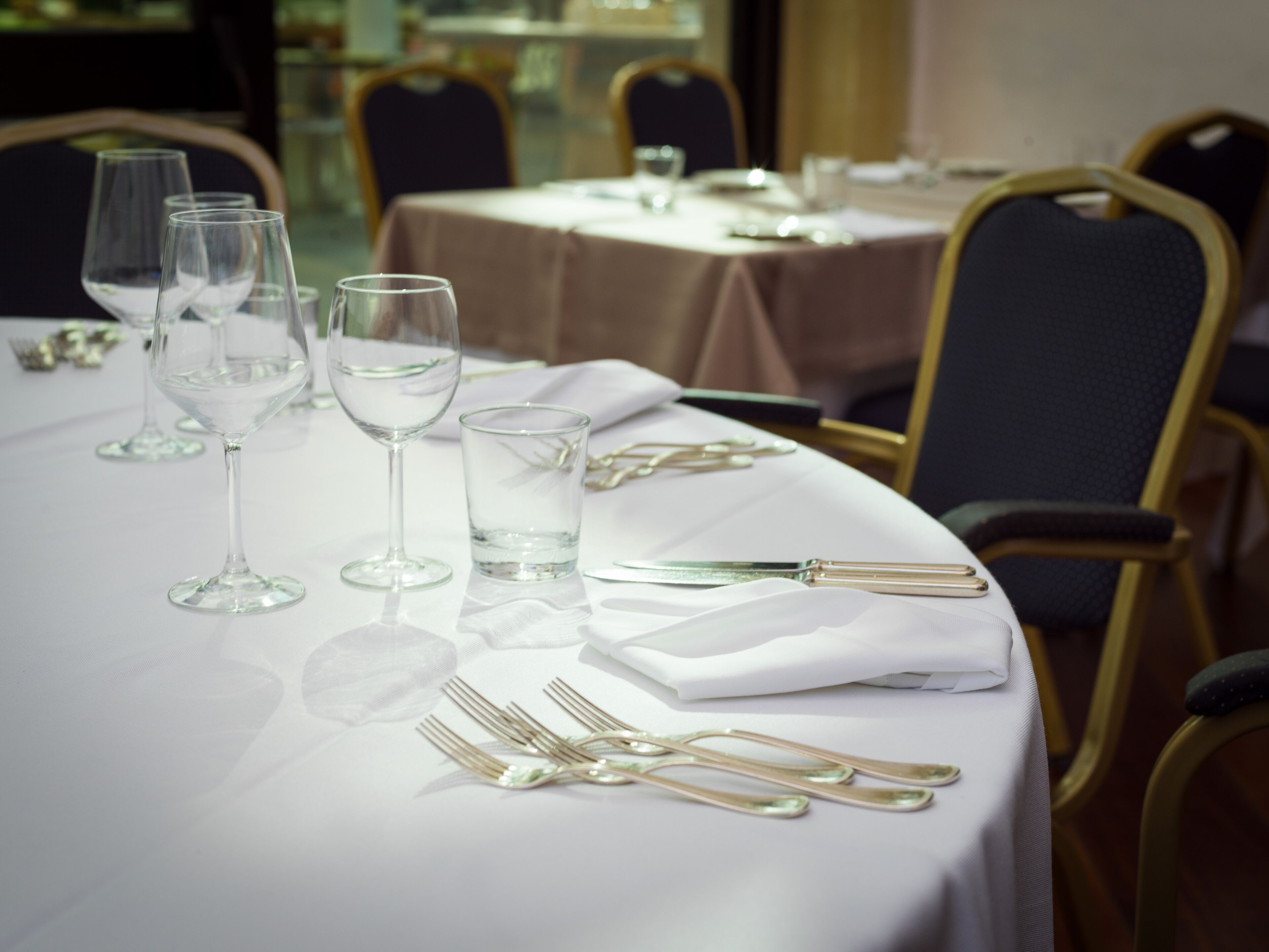 Une table à manger dressée avec des verres à vin, des verres à eau et des couverts.