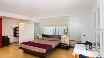 A modern hotel room with a large bed, bedside tables, a desk with a chair, and a view of the city through the window.