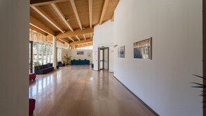 A spacious hallway with wooden beams, a blue sofa, and a potted plant. - Grand Hotel Tiziano e dei Congressi (Lecce)