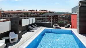 Une piscine sur le toit offrant une vue sur le paysage urbain, avec des bâtiments et une église visibles au loin.