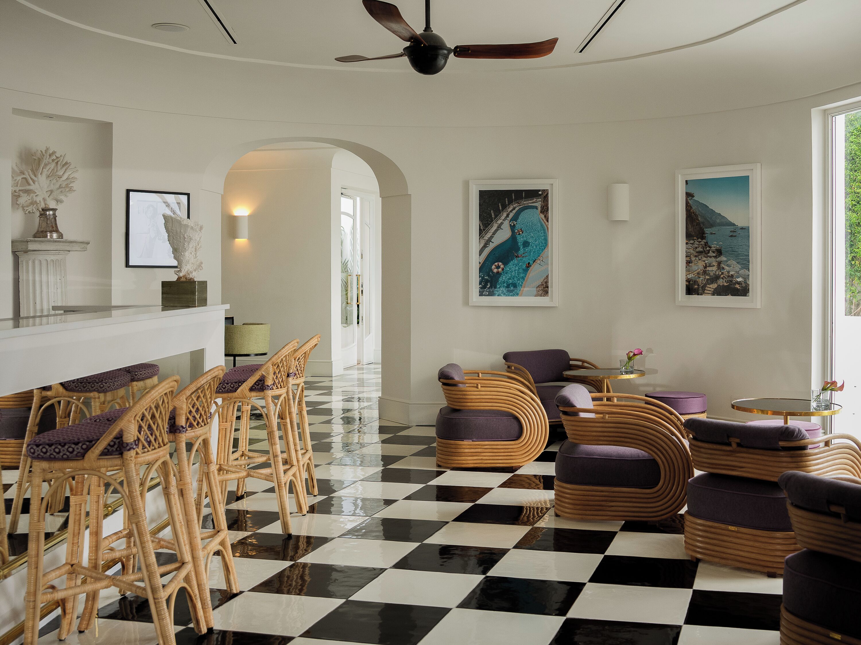 A hotel lobby with checkered flooring, wicker furniture, and artwork on the walls.