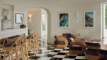 A hotel lobby with checkered flooring, wicker furniture, and artwork on the walls.
