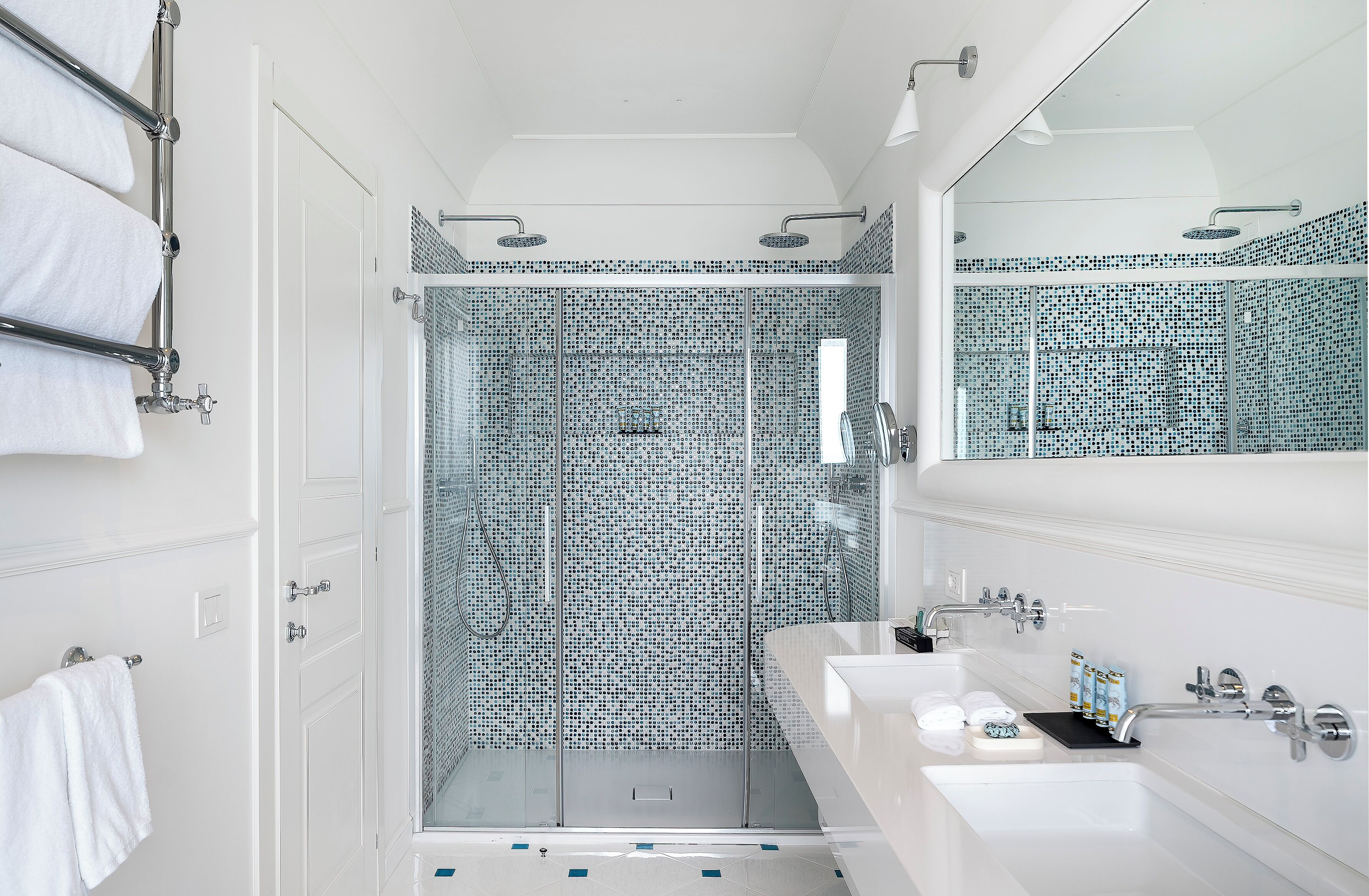 Un bagno moderno con doccia vetrata, sanitari bianchi e un grande specchio.