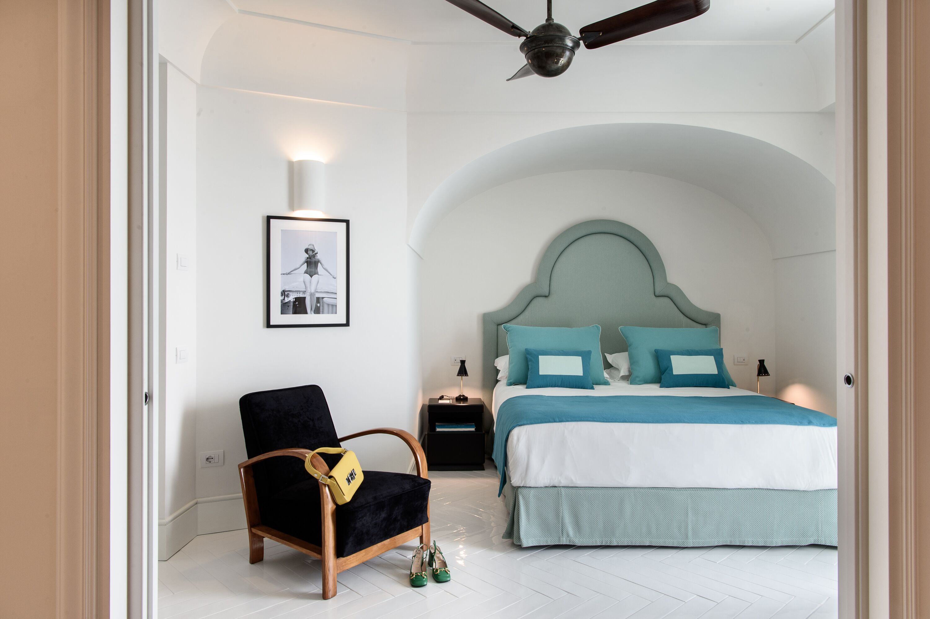 A bedroom with a bed, a chair, a nightstand, and a ceiling fan.