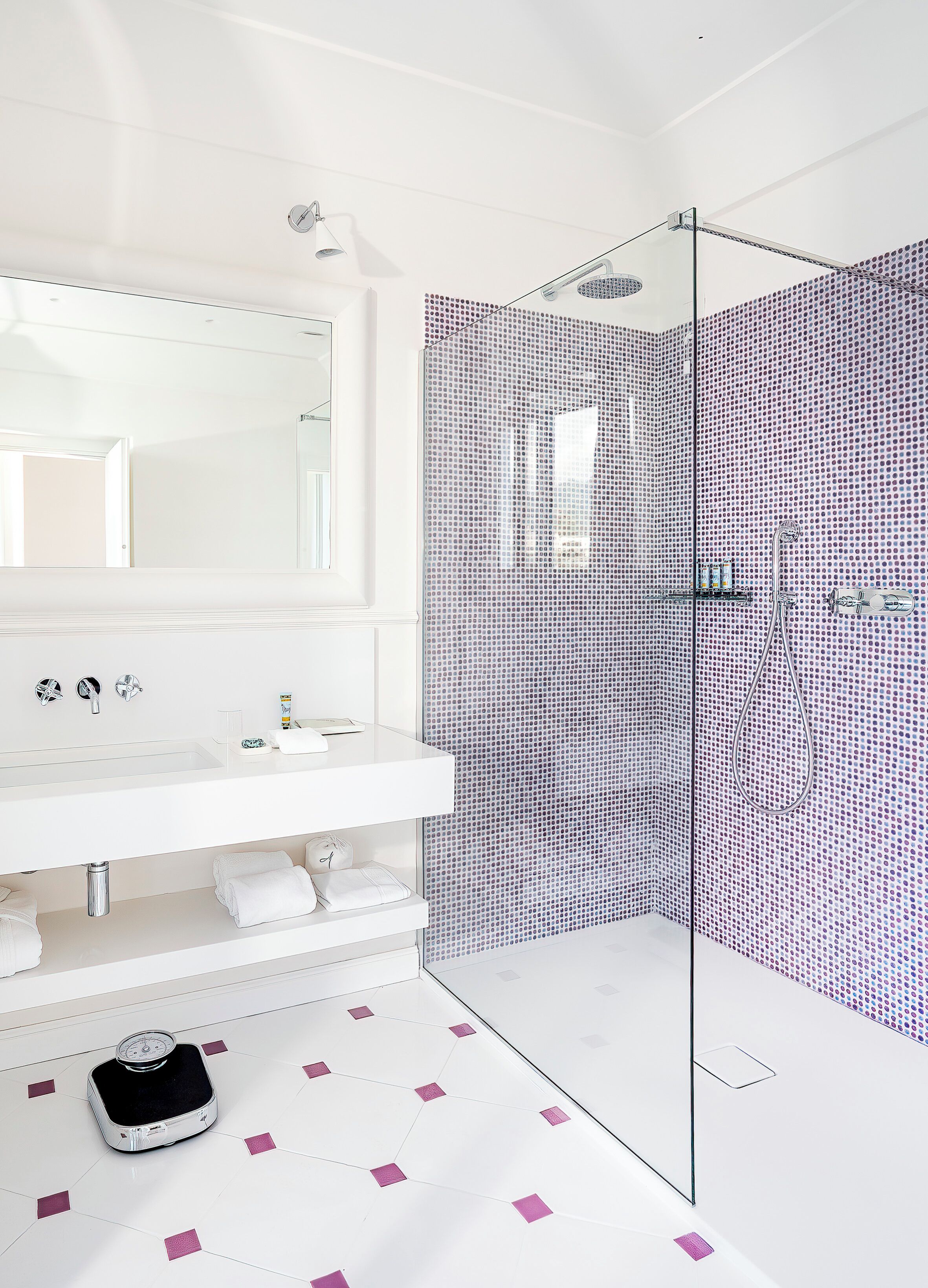 A modern bathroom with a large mirror, a white sink, and a shower area with a glass door.