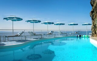 Una piscina al aire libre, sombrillas, sillones reclinables de piscina