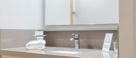 A bathroom with a white sink, a mirror, and a towel rack with folded towels.