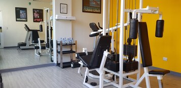 Un gimnasio con máquinas de cardio, equipo de levantamiento de pesas y una estación de hidratación.