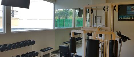 A gym with exercise equipment, a television, and a window with a view of greenery.