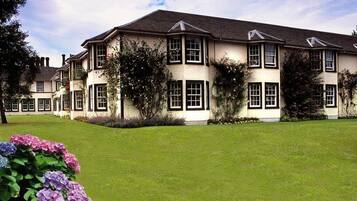 Stunning traditional building with a symmetrical facade, surrounded by a beautifully manicured lawn and lush gardens.
