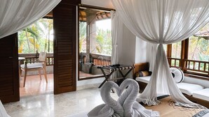 A room with a bed, white curtains, a wooden bench, and a view of palm trees. - Villa Sonia Ubud (Ubud)
