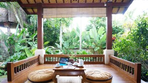 A wooden deck with a table, cushions, and a laptop. - Villa Sonia Ubud (Ubud)