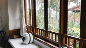 A room with a long, cushioned bench against a wall with large windows, offering a view of greenery outside. - Villa Sonia Ubud (Ubud)