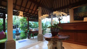 A lobby with a wooden ceiling, a stone table with a potted plant, a statue, and a painting on the wall. - Villa Sonia Ubud (Ubud)