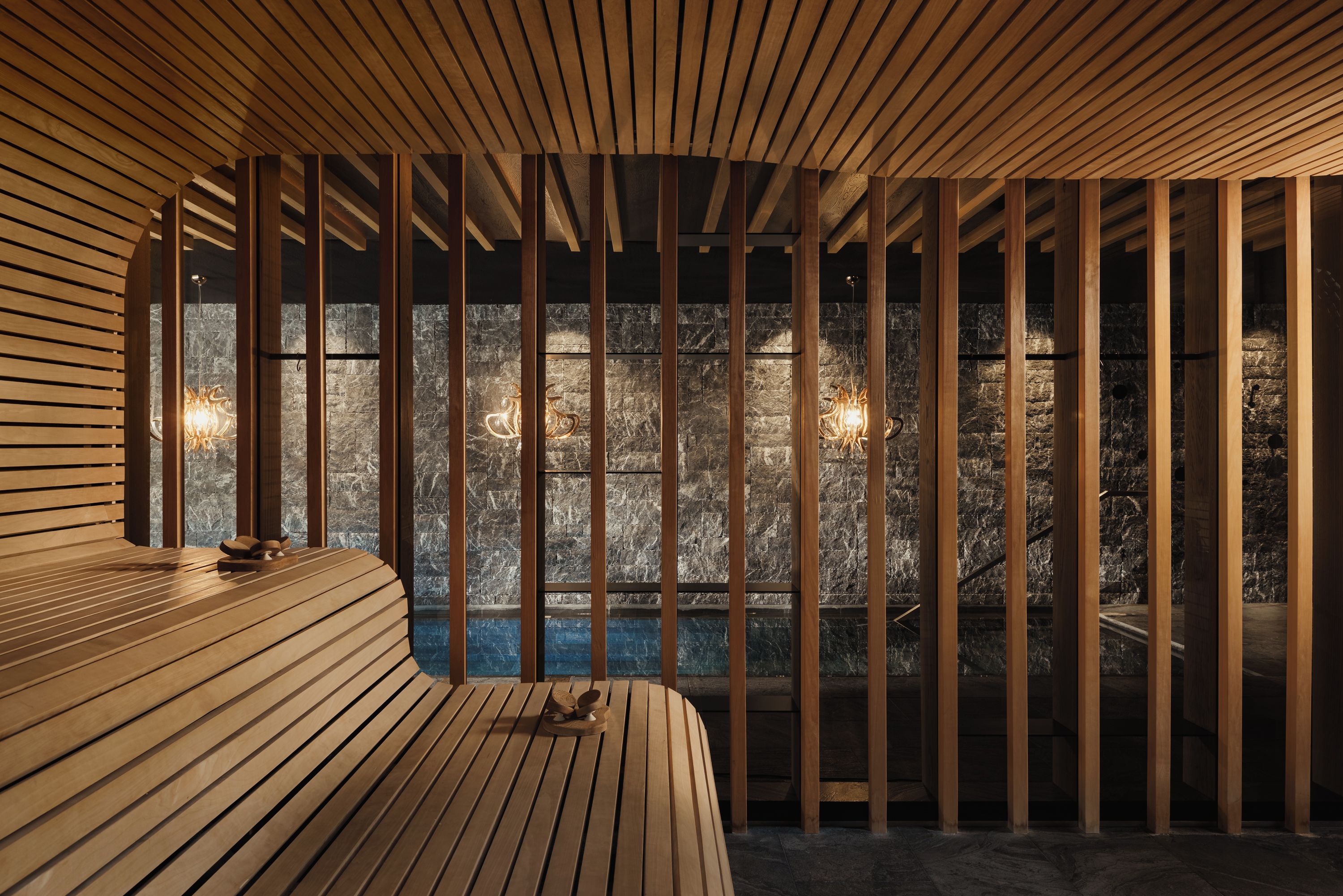 Une salle de spa avec des lambris en bois, un mur en pierre et un banc en bois.