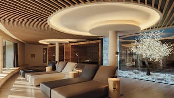 Un área de descanso moderna con techo de madera, una gran escultura de árbol y una zona de asientos con cojines.