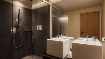 Ein modernes Badezimmer mit einer gläsernen Duschkabine, zwei Waschbecken und einer Holztür.