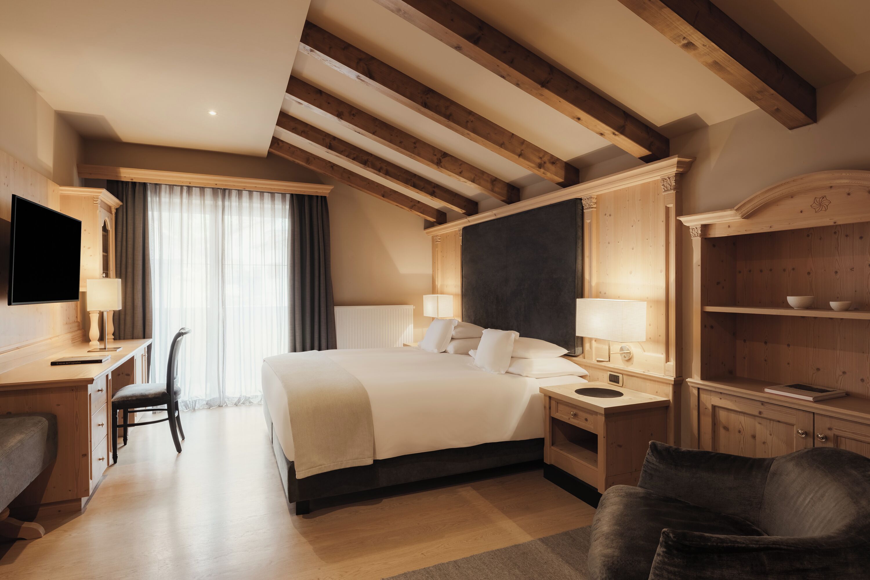 Habitación de hotel con una cama grande, mesitas de noche, un escritorio con silla, televisor y armario.