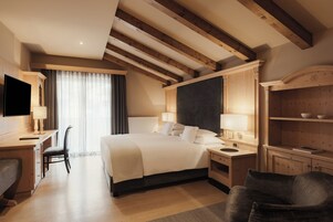 Habitación de hotel con una cama grande, mesitas de noche, un escritorio con silla, televisor y armario.