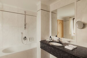 A modern bathroom with a bathtub, a sink, and a large mirror.