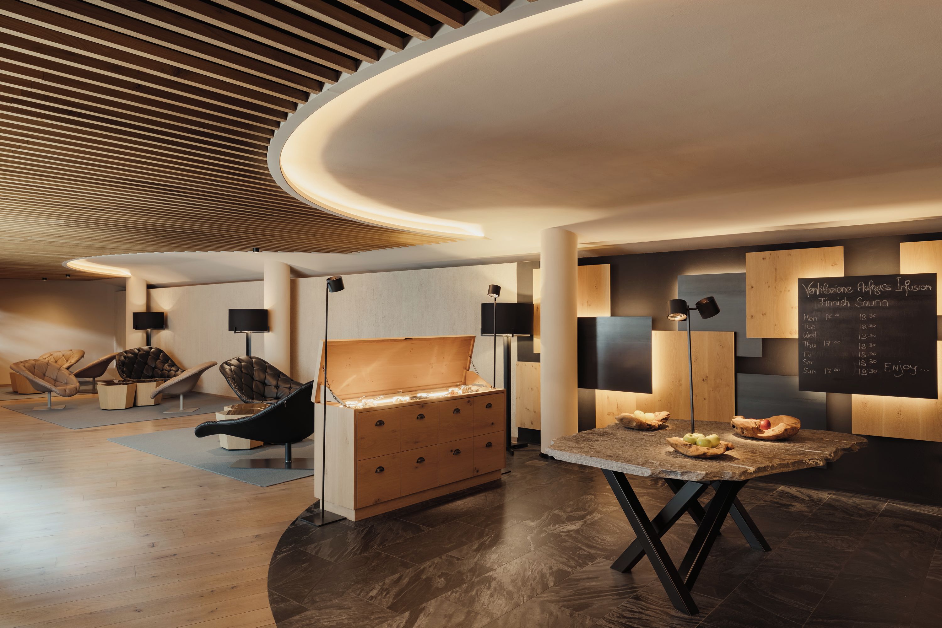 Um interior moderno com teto curvo, móveis de madeira e um quadro negro com um horário.