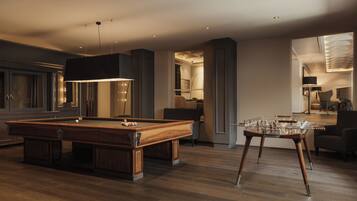A modern indoor setting with a pool table, a foosball table, and a bar area.