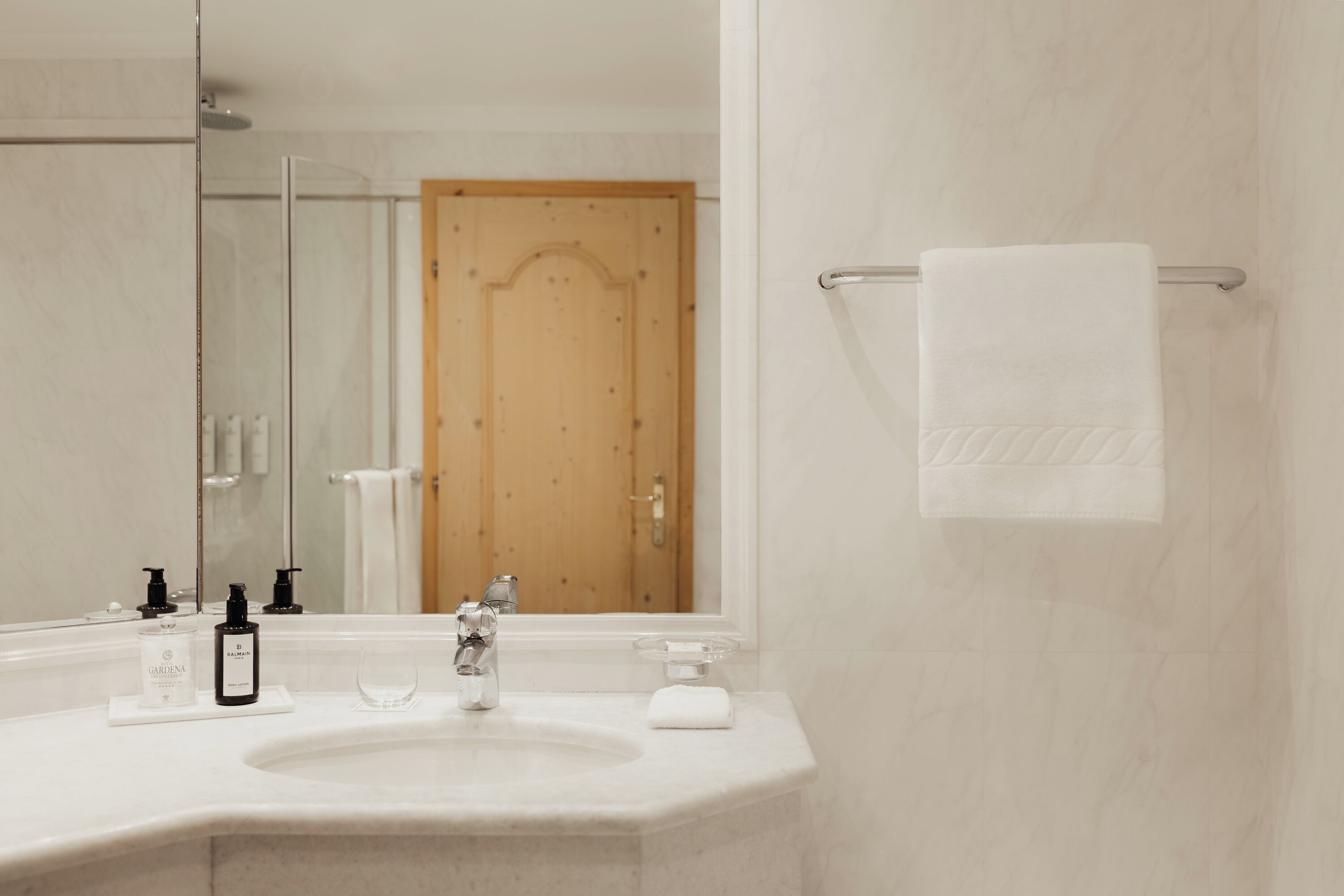 Un baño de hotel con un espejo grande, un lavamanos y un perchero para toallas.