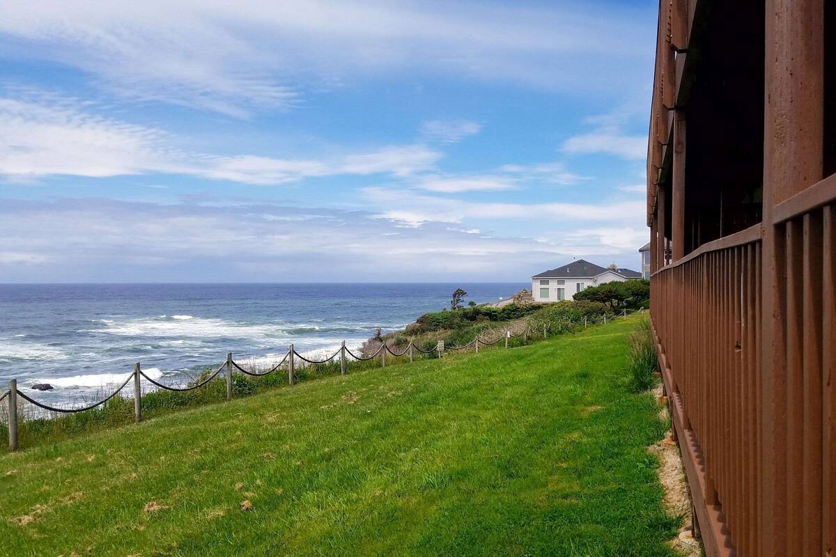 Une vue sur la côte, avec une pente herbeuse, une clôture en bois et un bâtiment en arrière-plan.