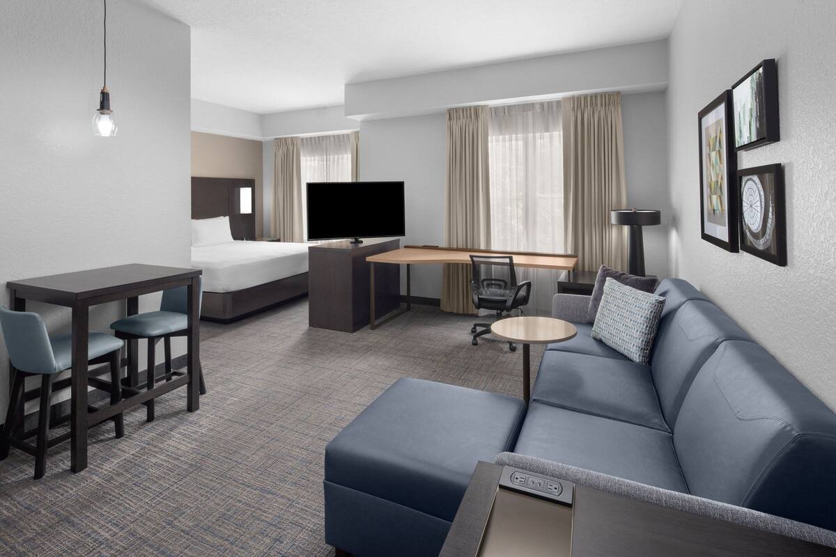 Une chambre d’hôtel comprenant un lit, un bureau, une télévision, un canapé et une table basse.