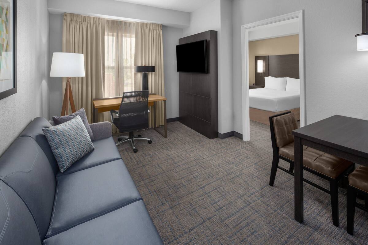 Une chambre d’hôtel équipée d’un canapé, d’un bureau, d’une télévision, d’un lit et d’une table à manger.