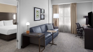 A hotel room with a bed, a sofa, a desk, a chair, and a TV. - Residence Inn by Marriott Tampa Oldsmar (Oldsmar)